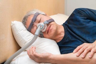 Man wearing CPAP headgear during his sleep